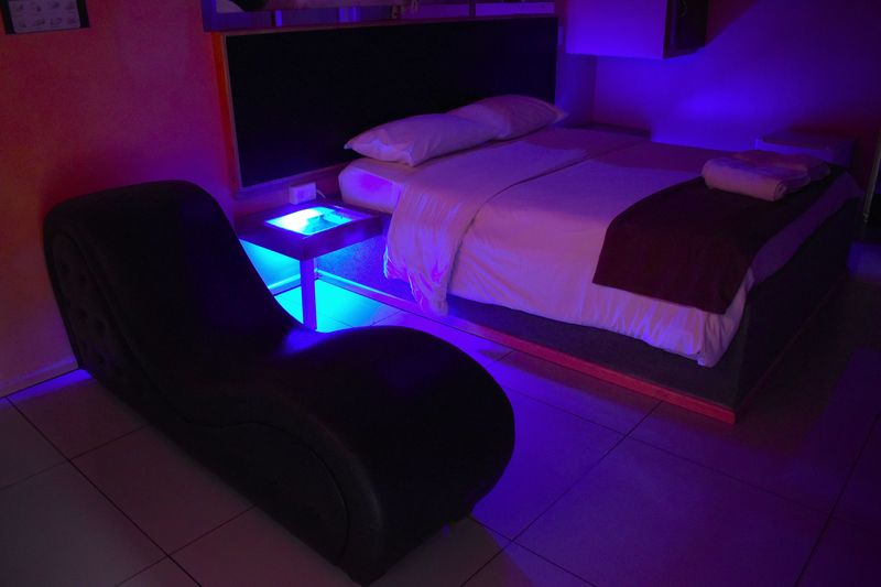 Habitación con luz azul, cama doble y sillón tántrico
