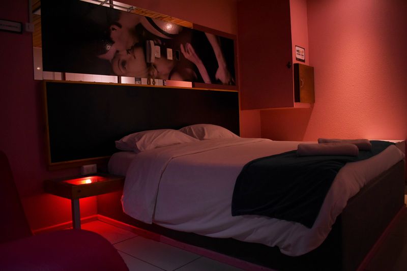 Cama doble con luz roja bajo el velador