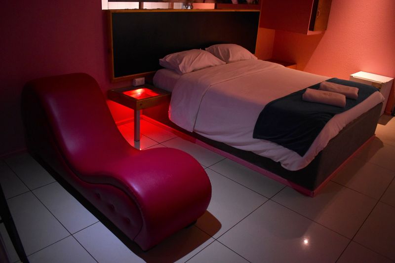 Habitación con luz roja, cama doble y sillón tántrico